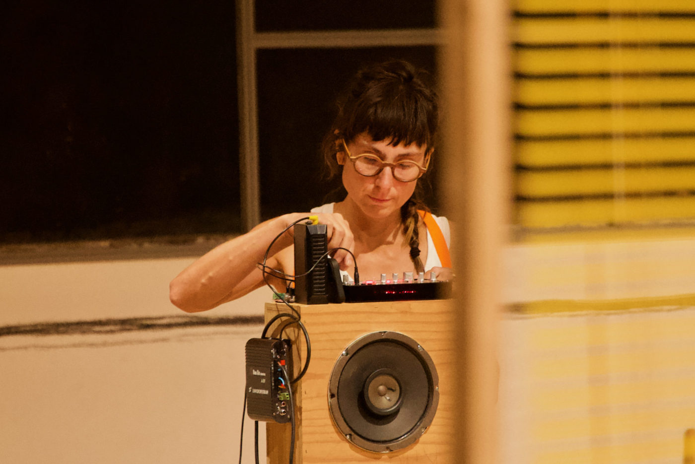 We see an artist before a speaker. She adds a new cable to the speaker.