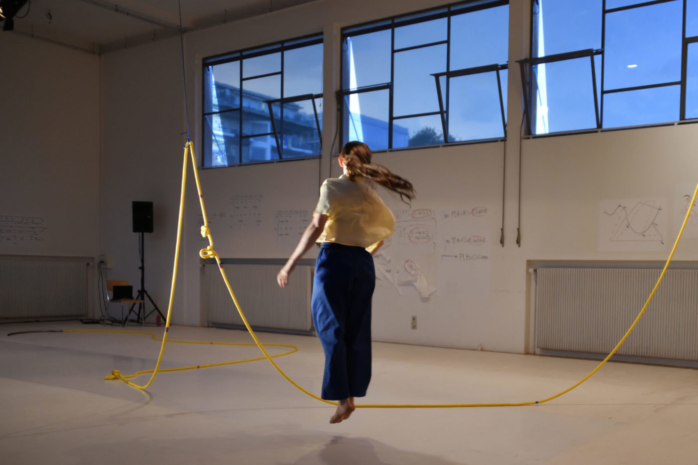 The dancer Bianca Berger practices jump rope. The big yellow rope is fixed at the extremity of two other ropes fixed on the ceiling.