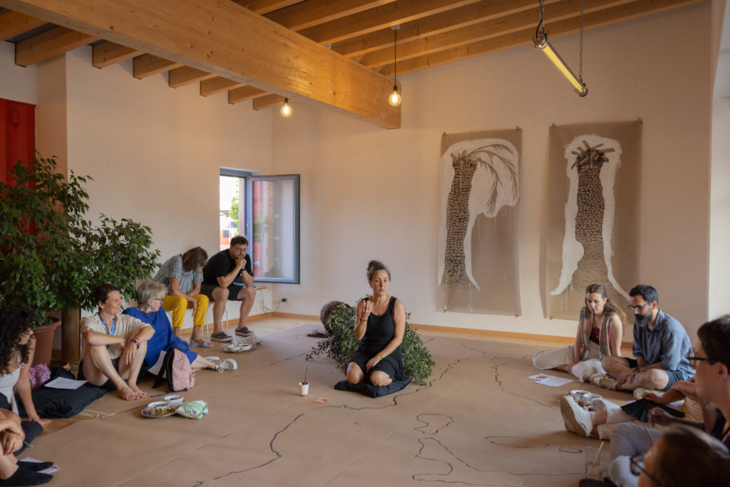 The artist Samah Hijawi stands on a floor recovered by paper on which she can draw, surrounded by the people from the public.
