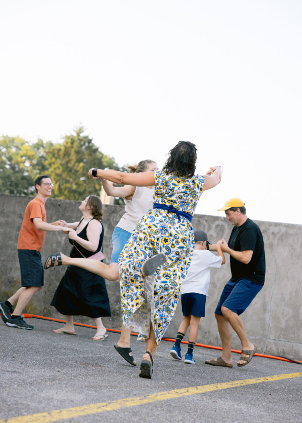 We see couples of people dancing the waltz. In the foreground we see a woman from behind who has only the tip of her foot touching the floor. She is elevated in the air.