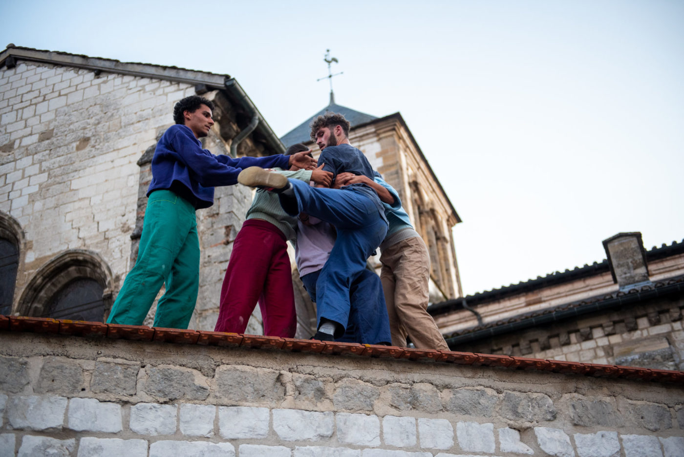 The five acrobats from la horde dans les pavés are on the roof of a building that looks like a church. They are doing acrobatics.