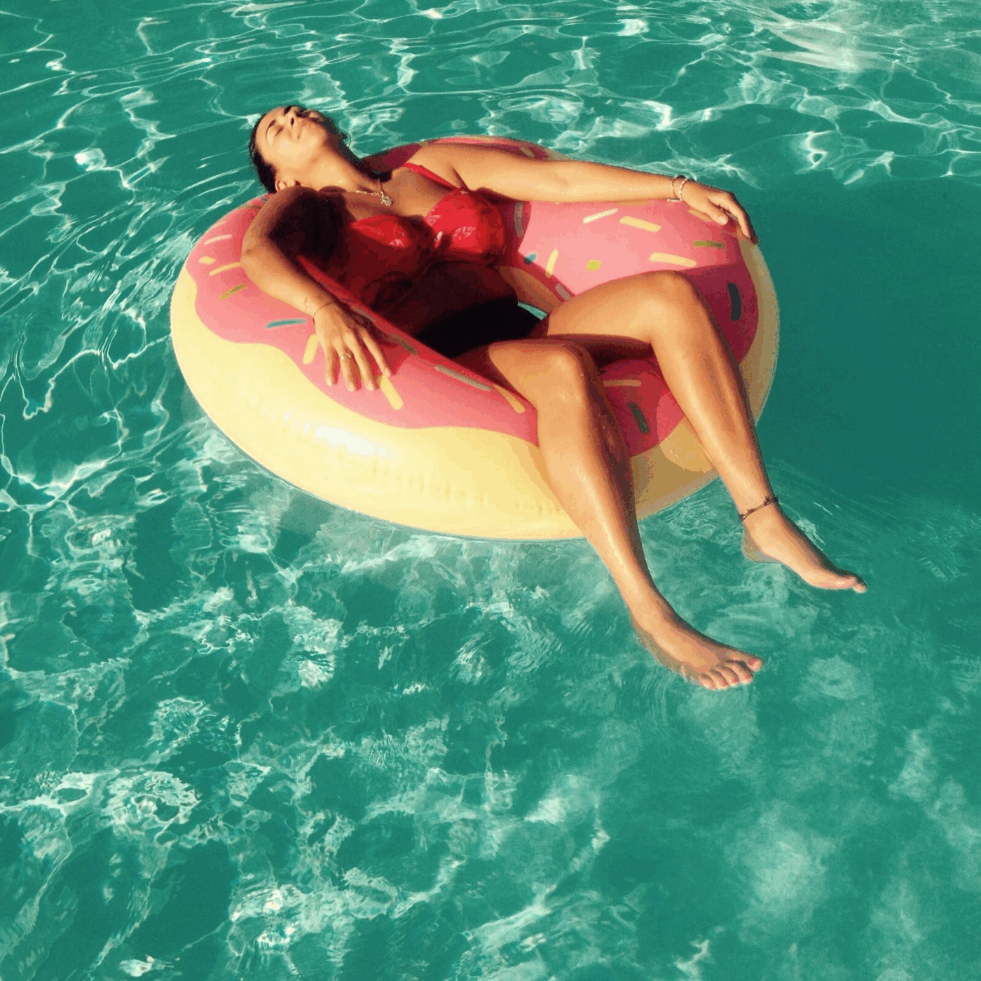 Portrait of ANITA KIRPPIS, in a float ring, floating in a pool.