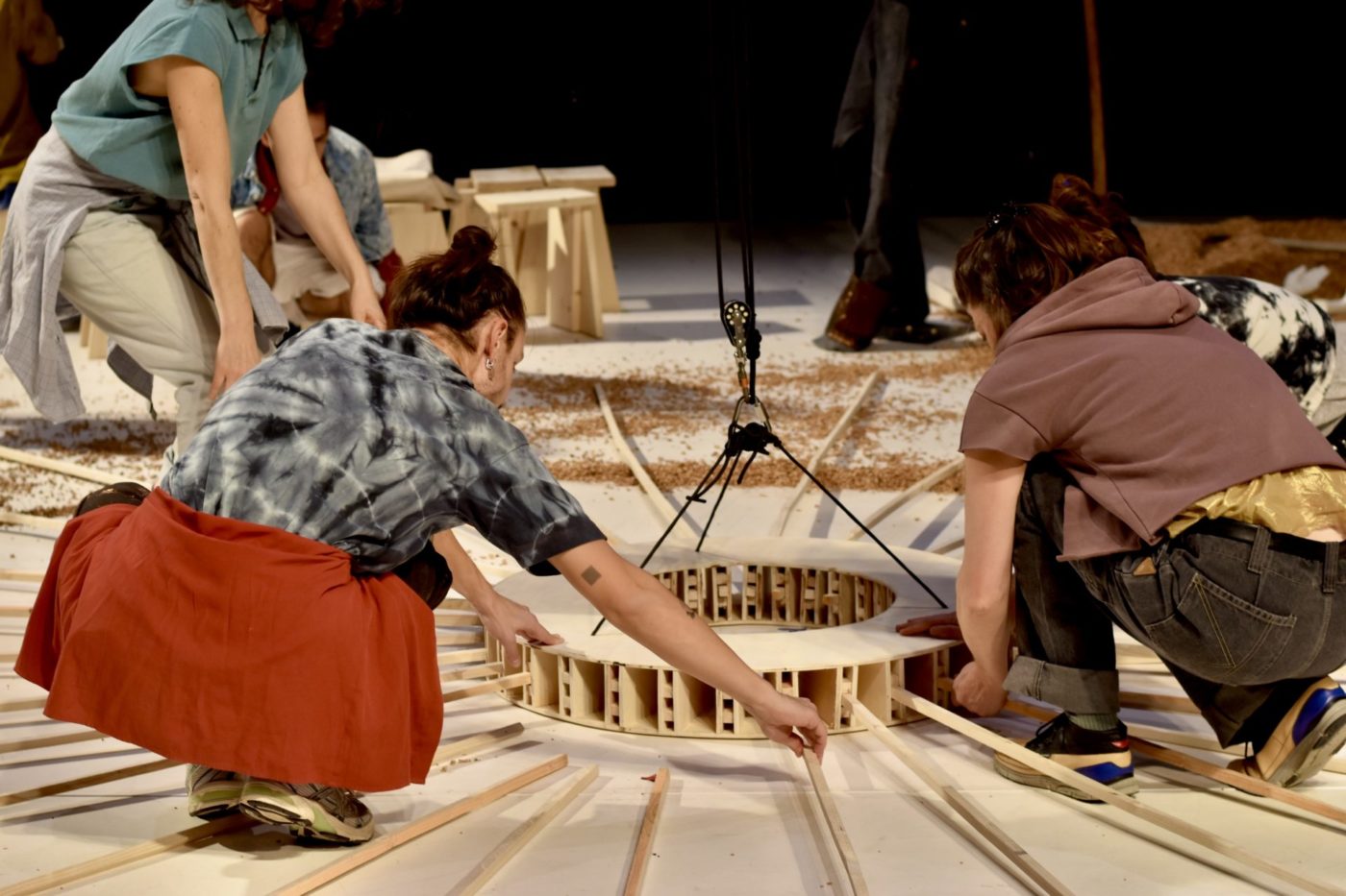 Several people are building a wooden structure on stage.
